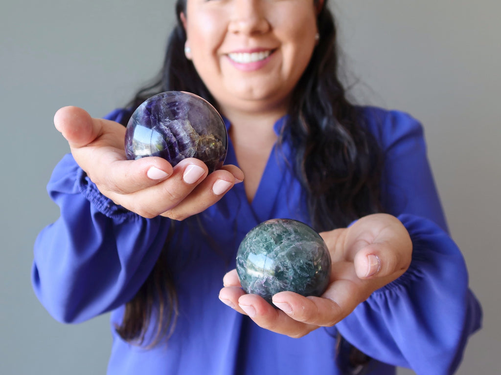 woman holding two fluorite spheres