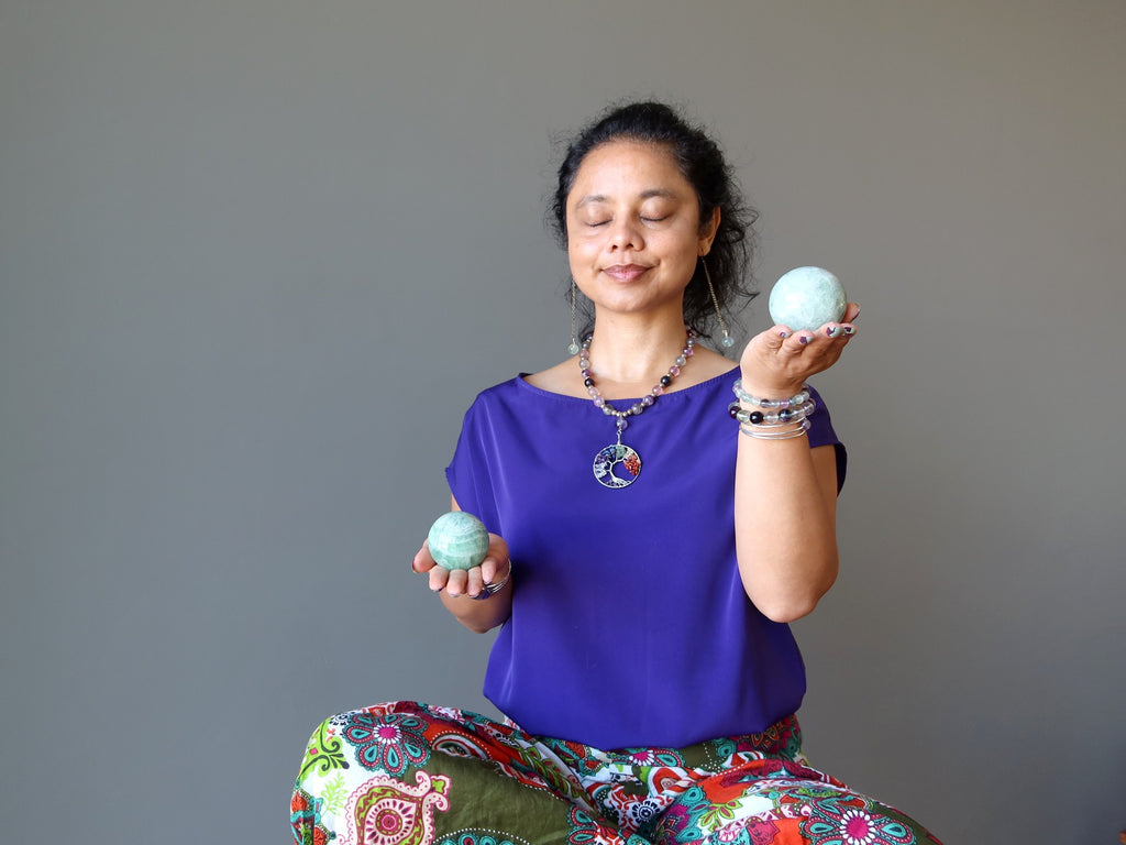 woman meditating with green fluorite spheres