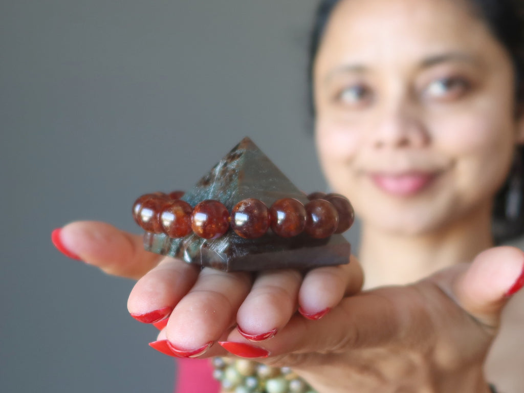 sheila of satin crystals holding a garnet pyramid with a hessonite bracelet