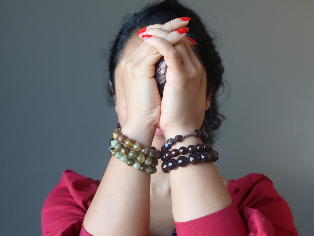 woman holding garnet heart in both hands and wearing garnet bracelets