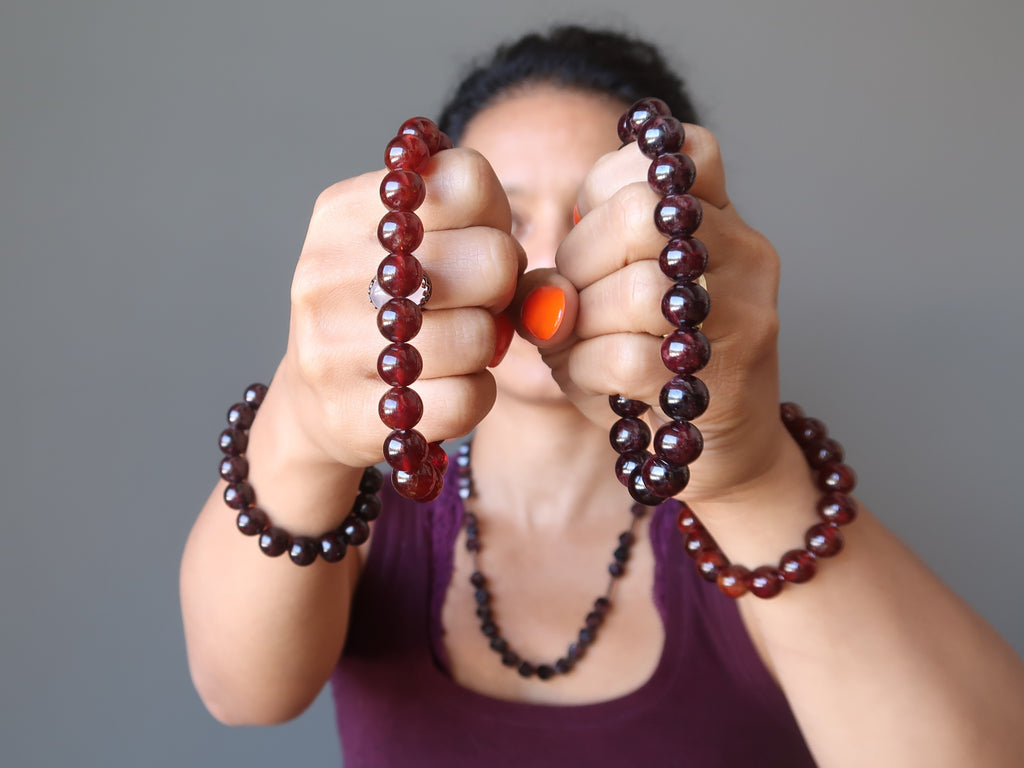 sheila of satin crystals holding red and hessonite garnet stretch bracelets