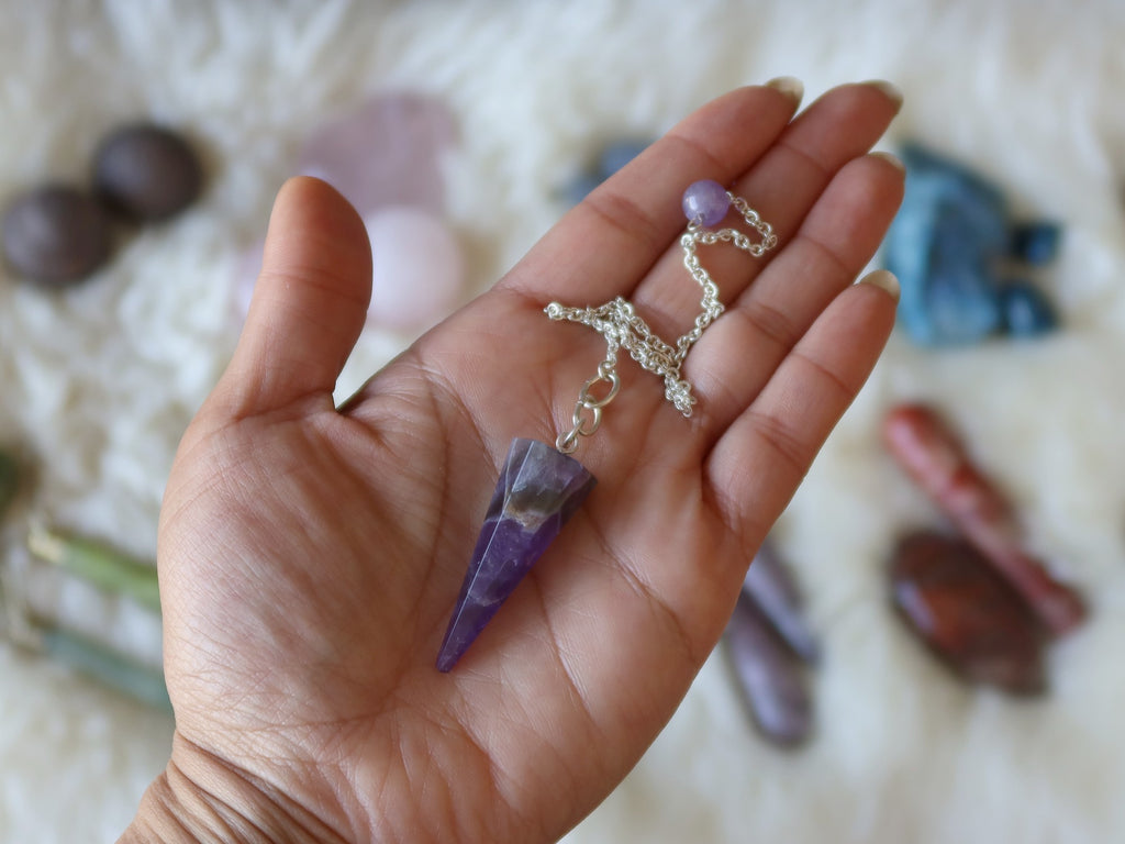 amethyst pendulum in palm of hand