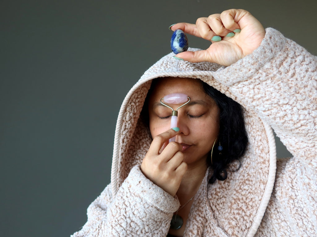 woman holding sodalite egg and using pink rose quartz roller