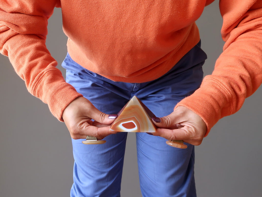 holding a carnelian pyramid at the sacral chakra