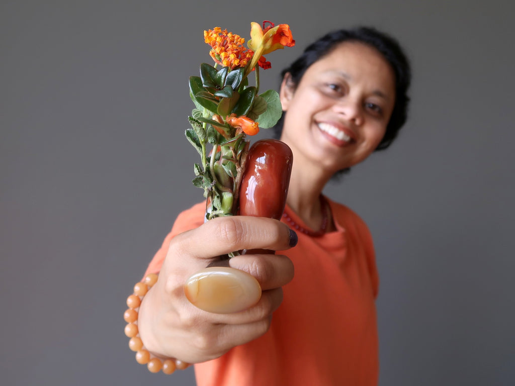 sheila of satin crystals holding out a bouquet of orange flowers and carnelian