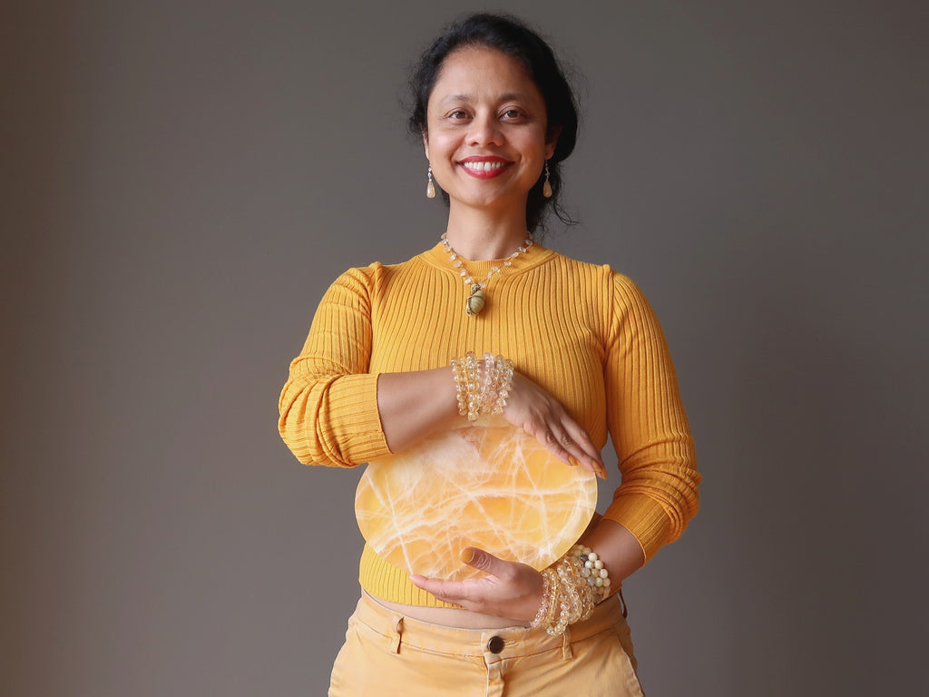 sheila of satin crystals holding a yellow calcite platter at her solar plexus chakra