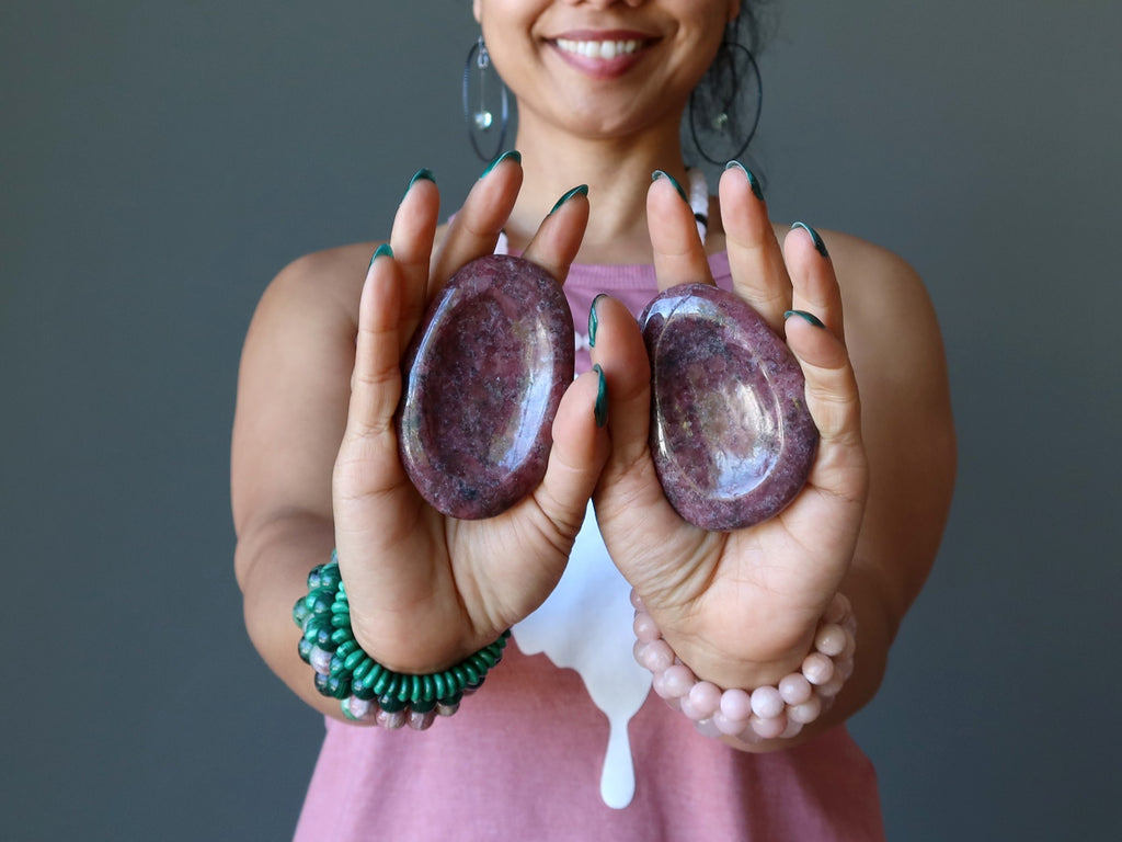 sheila of satin crystals holding out rhodonite worry stones in her palms
