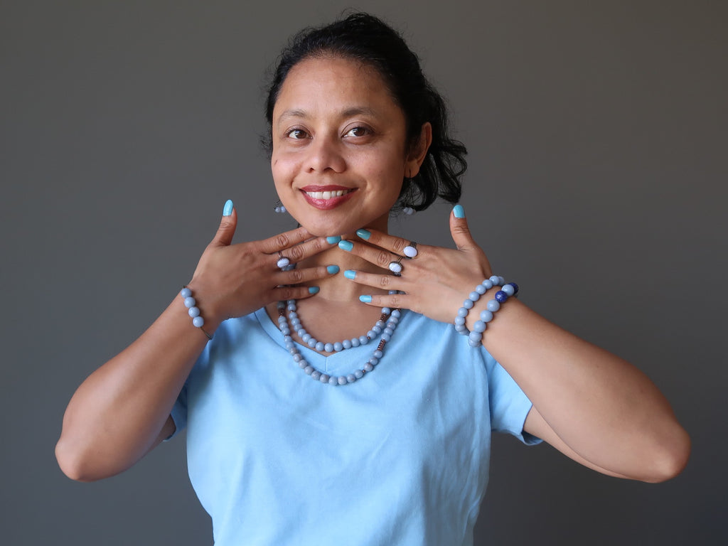 sheila of satin crystals in blue and blue jewelry touching her throat chakra