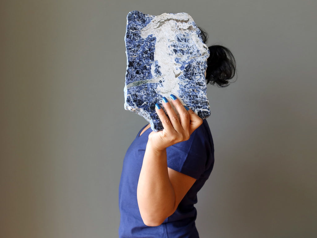 sheila of satin crystals holding up a sodalite slab