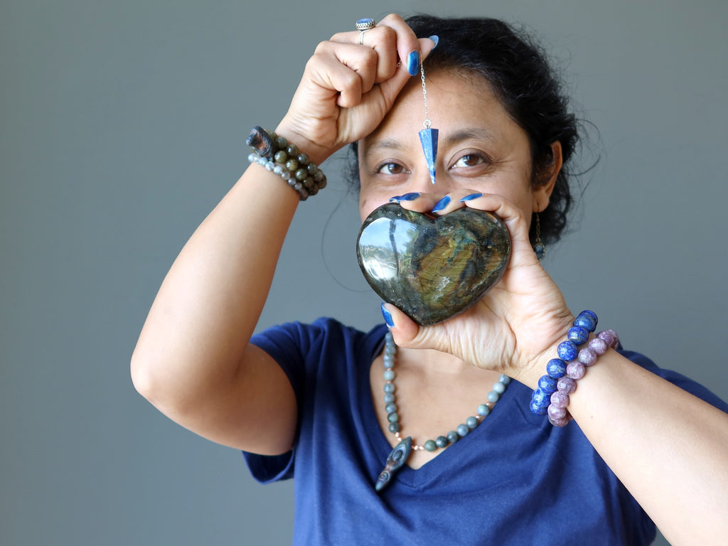 sheila of satin crystals holding a labradorite heart and lapis pendulum for the third eye chakra