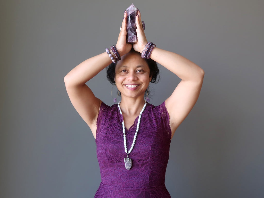sheila of satin crystals dressed in purple holding a fluorite tower at her crown chakra