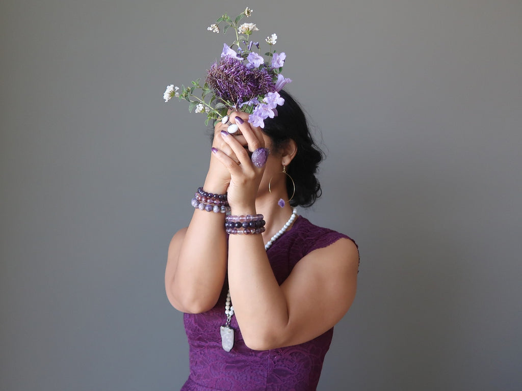 sheila of satin crystals dressed in purple holding purple and white flowers at her crown chakra