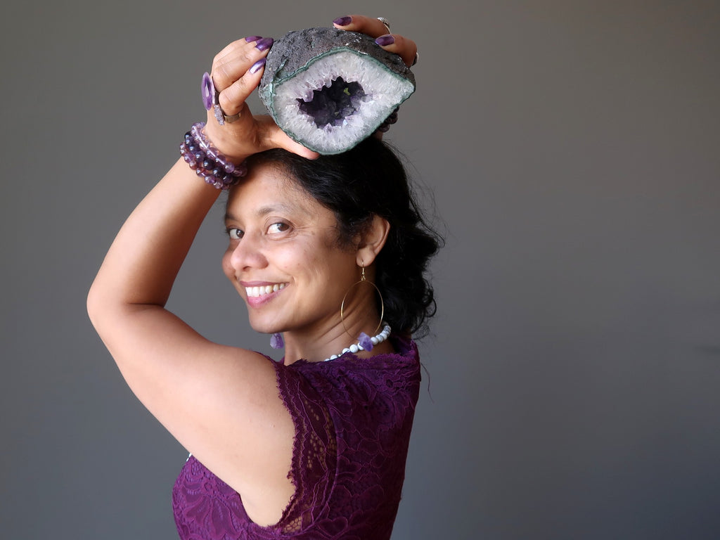 sheila of satin crystals holding an amethyst geode at her crown chakra