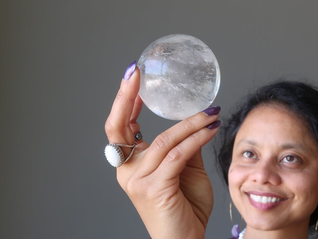 sheila of satin crystals holding up a clear quartz sphere