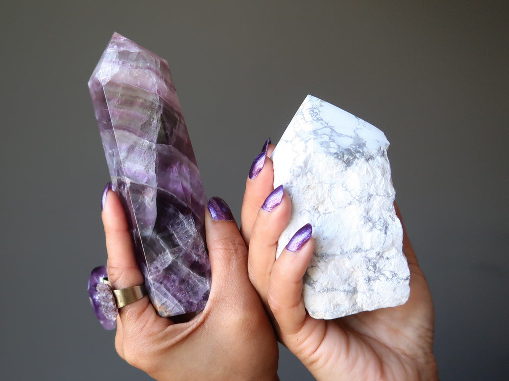 hands holding a fluorite tower and howlite tower
