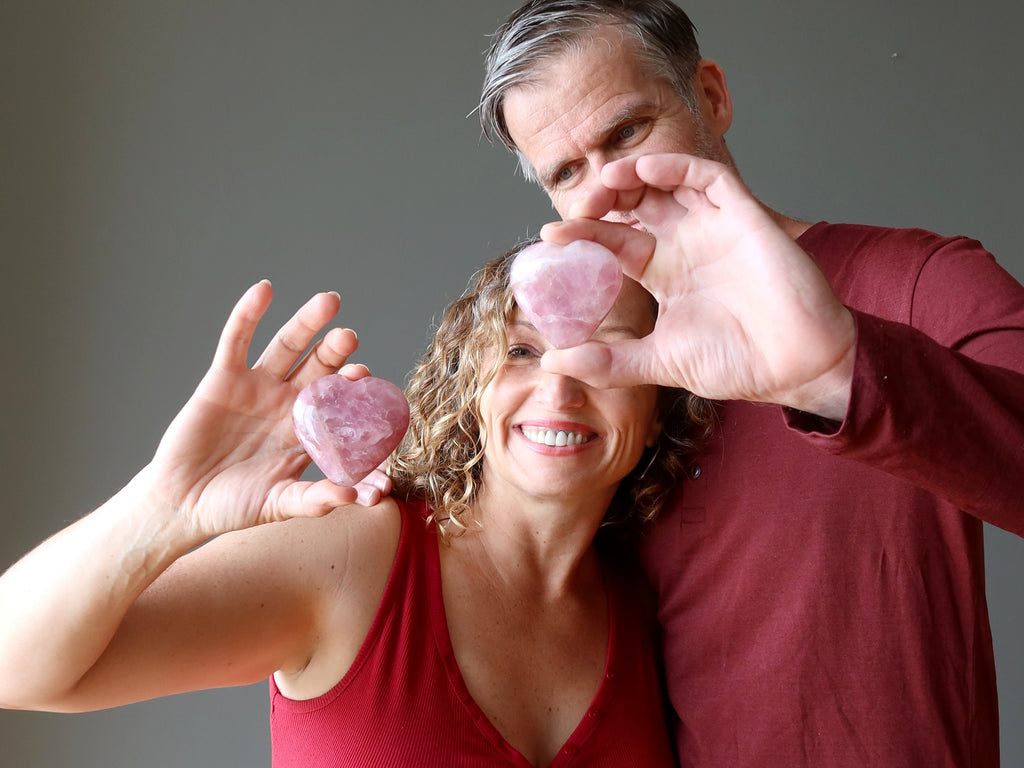 man and woman holding pink rose quartz hearts