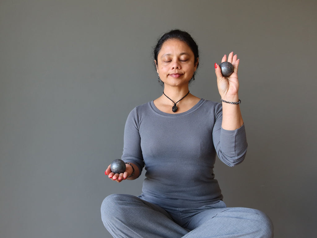 woman meditating with hematite spheres
