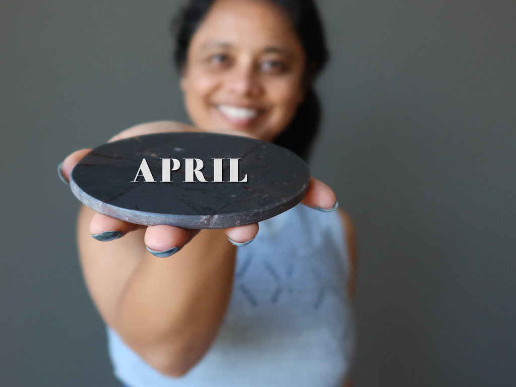 woman holding hematite circle with word APRIL