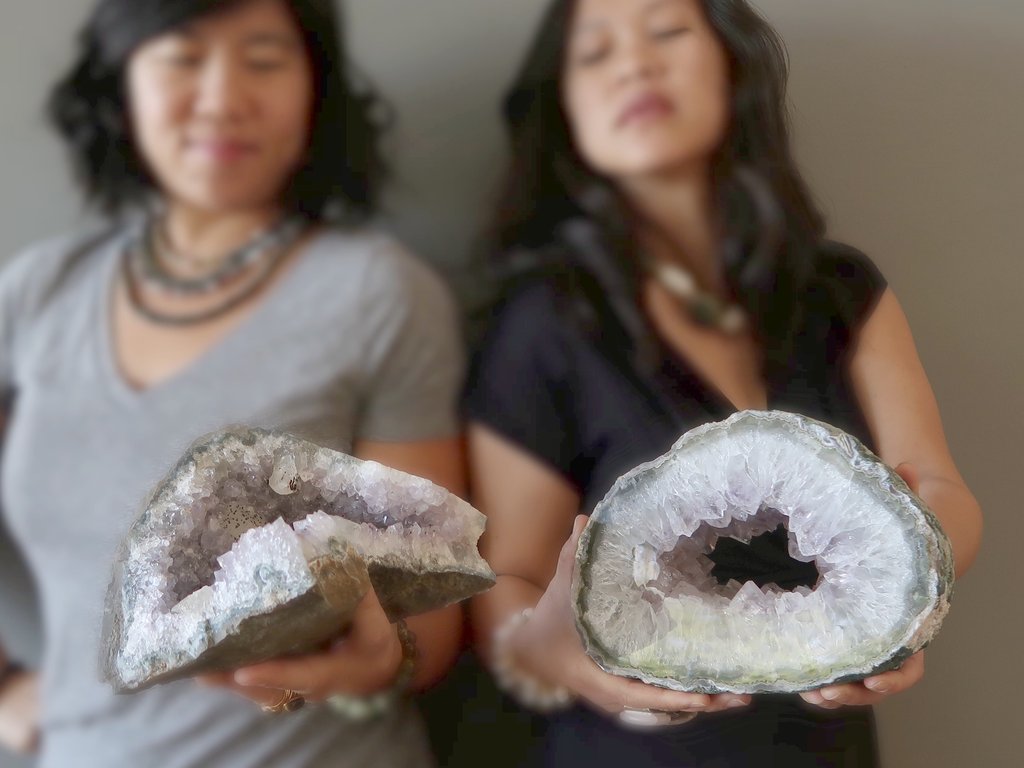 two women holding purple amethyst geodes