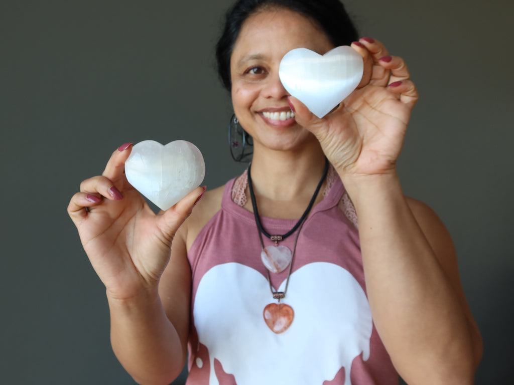 woman holding two white selenite hearts