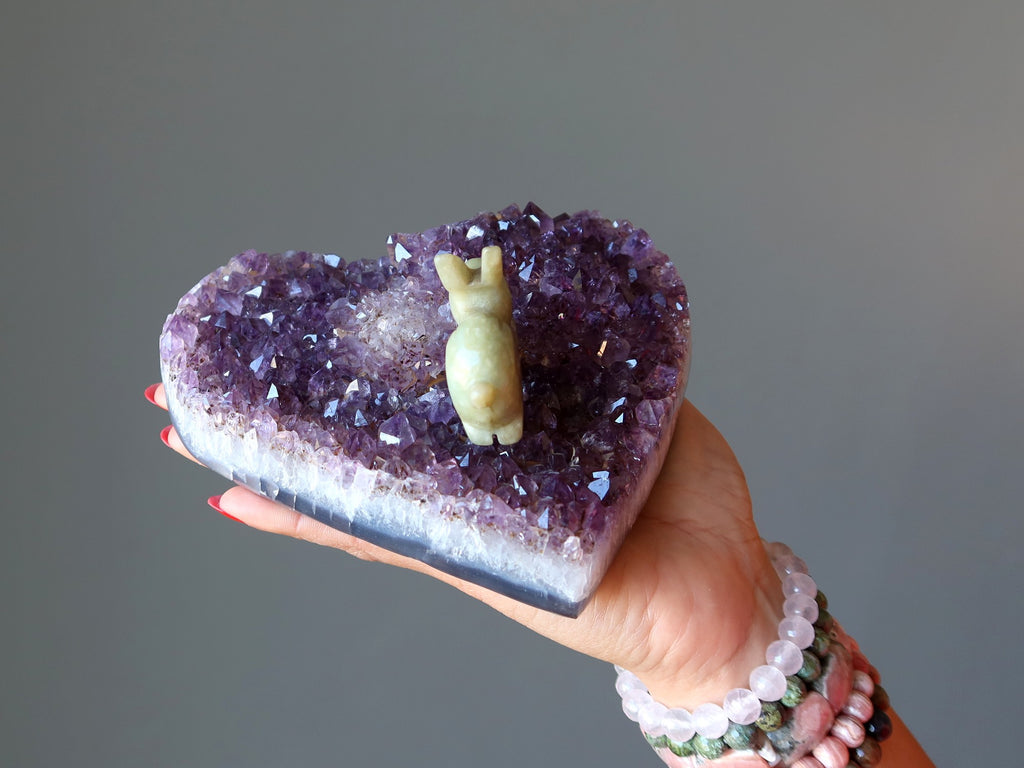 hand holding amethyst geode cluster heart with jade rabbit