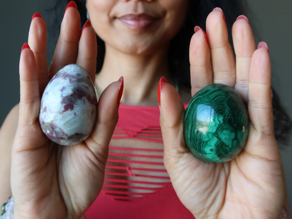 red tourmaline and malachite egg in palms of hands