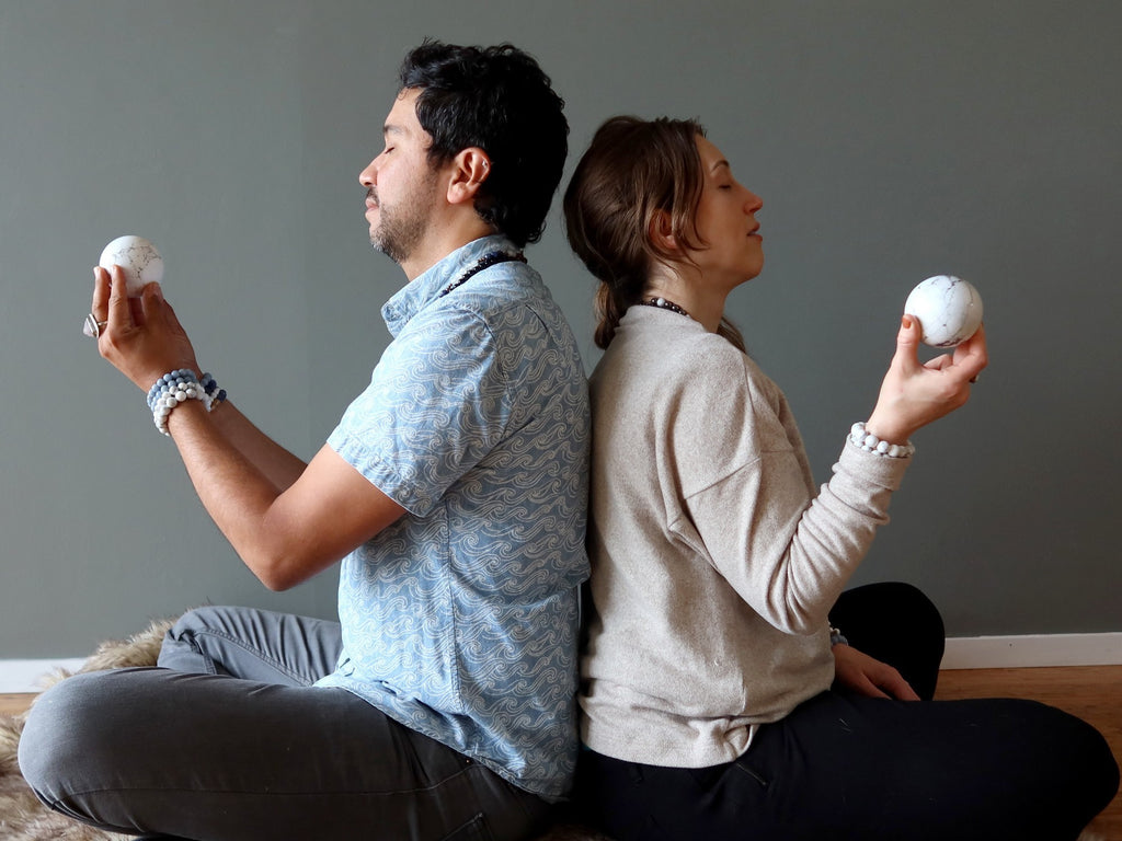 man and woman back to back meditating with howlite spheres