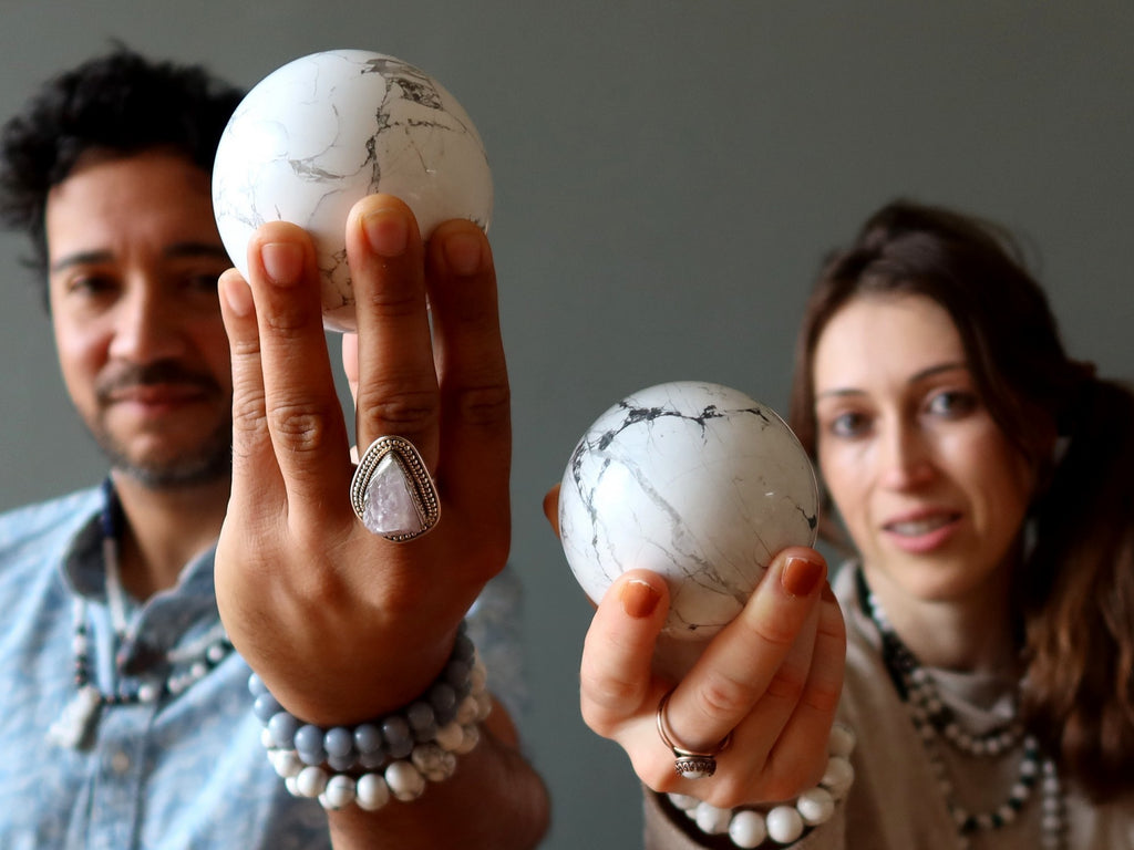 man and woman holding howlite spheres