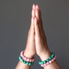 hands in meditation wearing rhodochrosite and malachite stone stretch bracelets