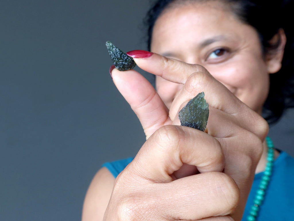 sheila of satin crystals holding two moldavite pieces