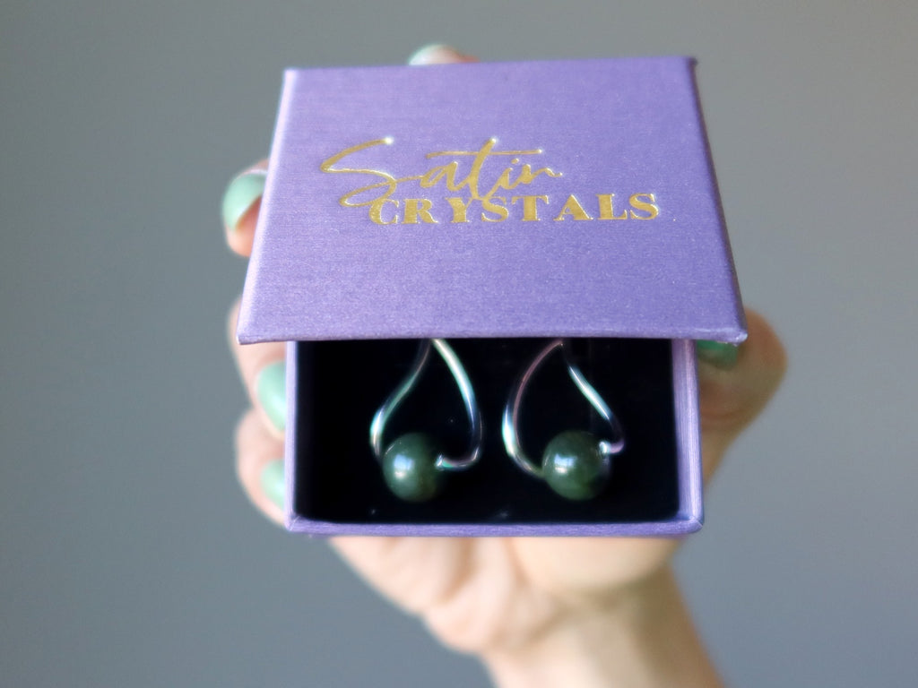 hand holding purple satin crystals jewelry box with jade earrings