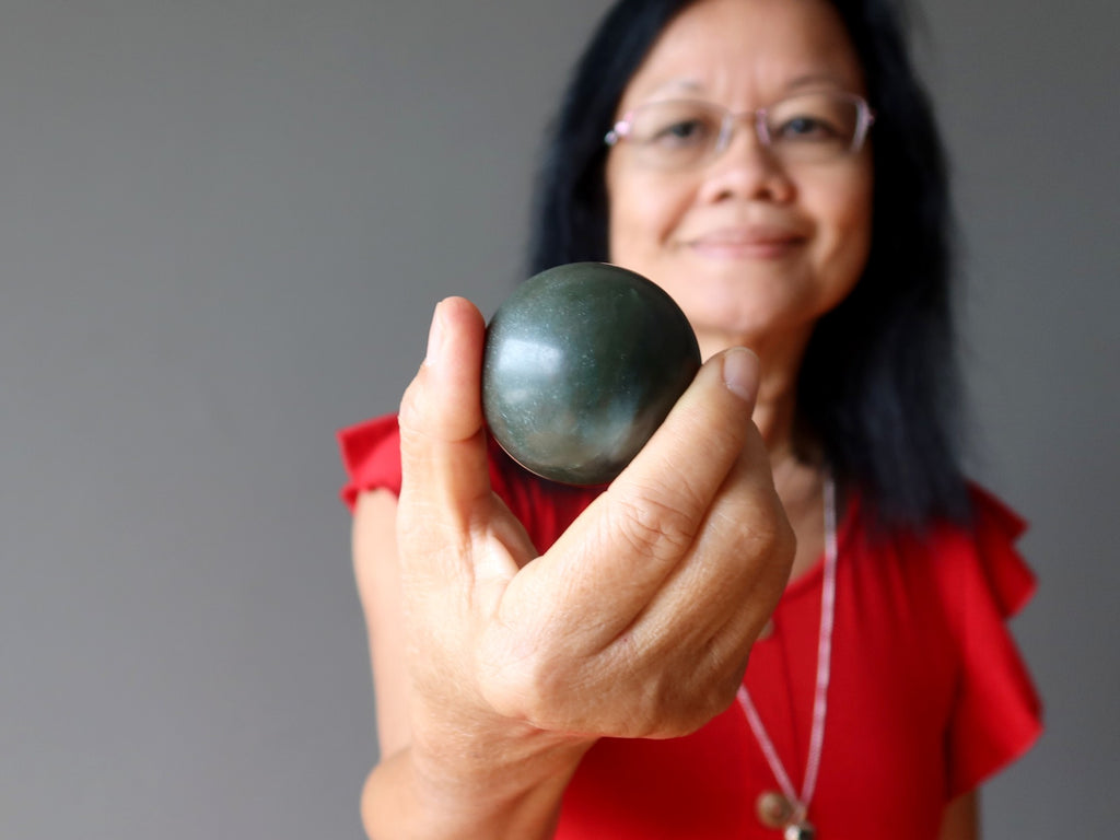 woman holding dark green jade sphere