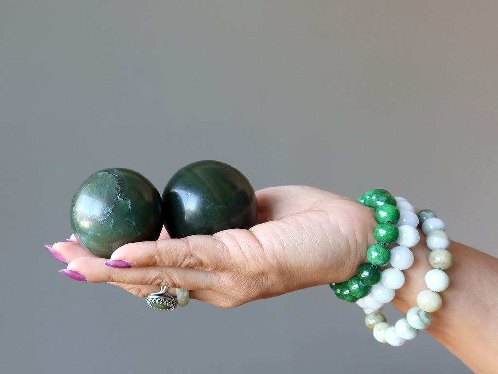 hand wearing jade bracelet, rings, holding jade spheres