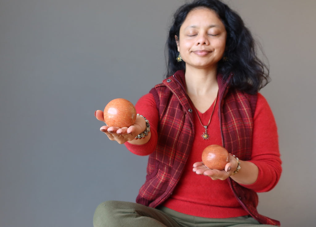 female meditating with two red jasper crystal balls