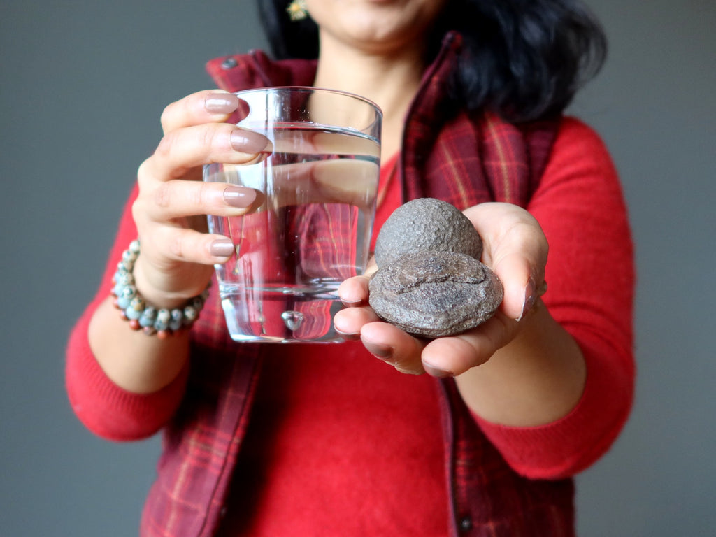 female holding moqui marbles and a glass of water