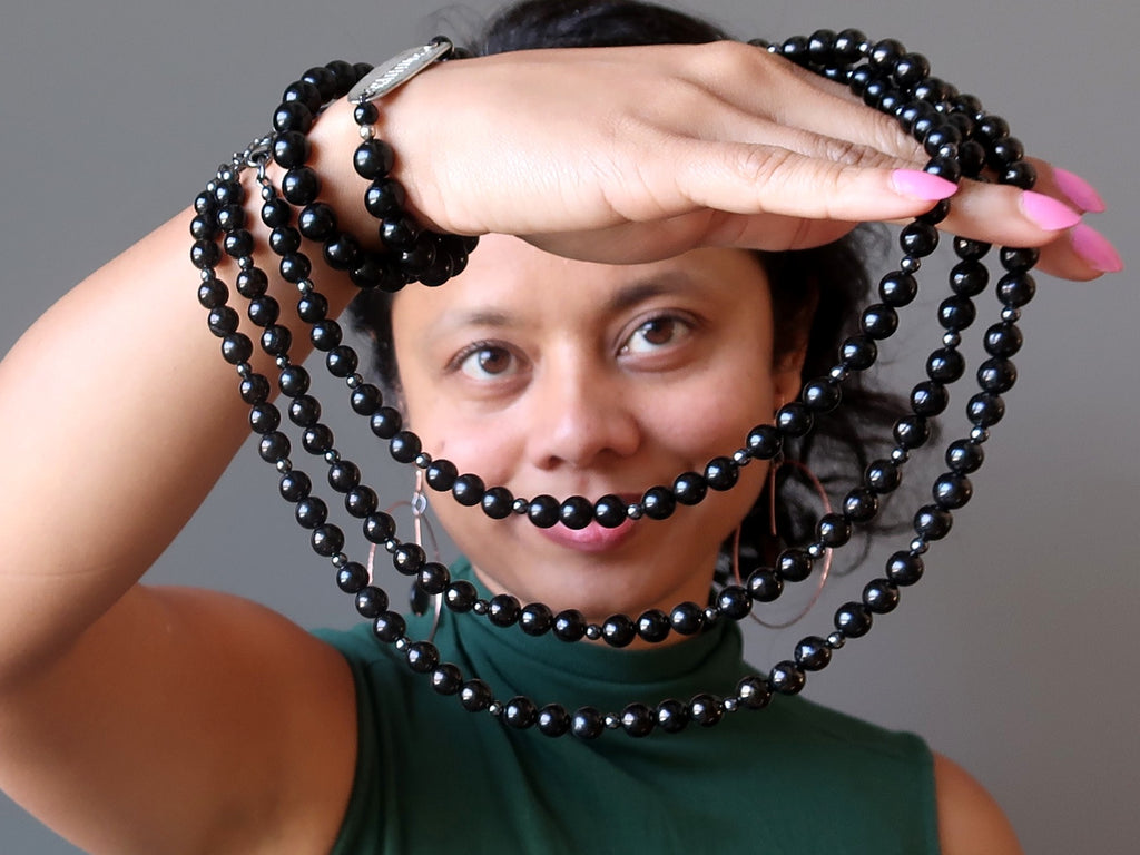 woman holding three jet beaded necklaces