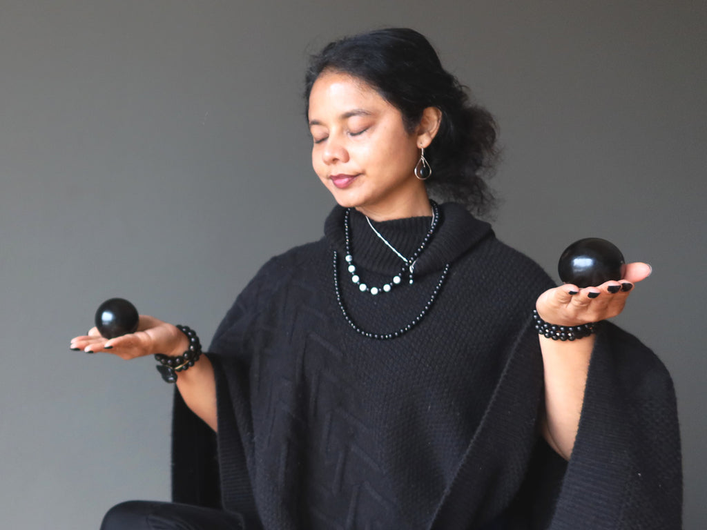 woman meditating with jet stone spheres