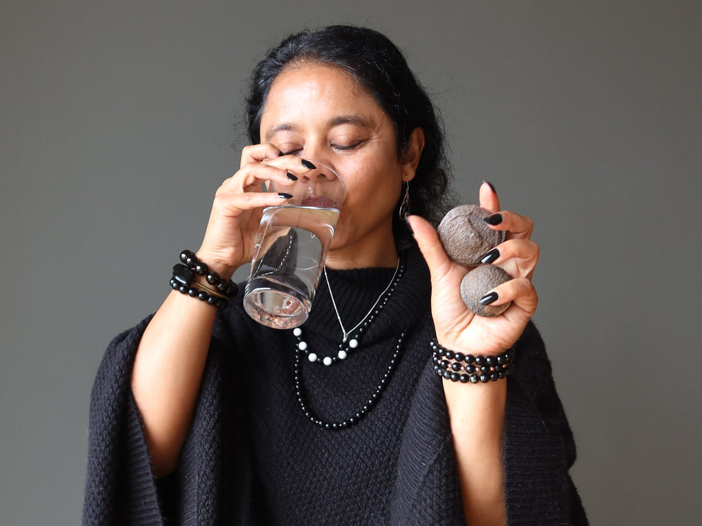 sheila of satin crystals drinking a glass of water holding moqui marbles