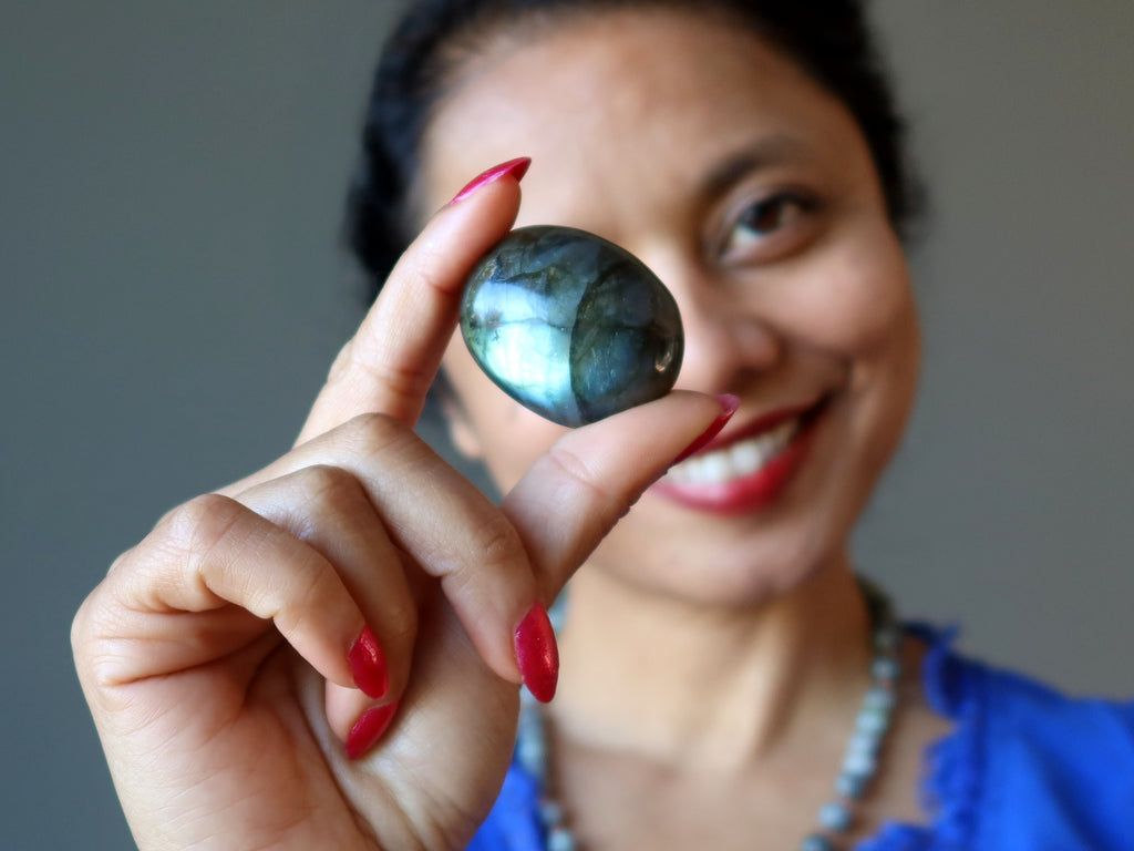 sheila of satin crystals holding a labradorite oval cabochon to her eye