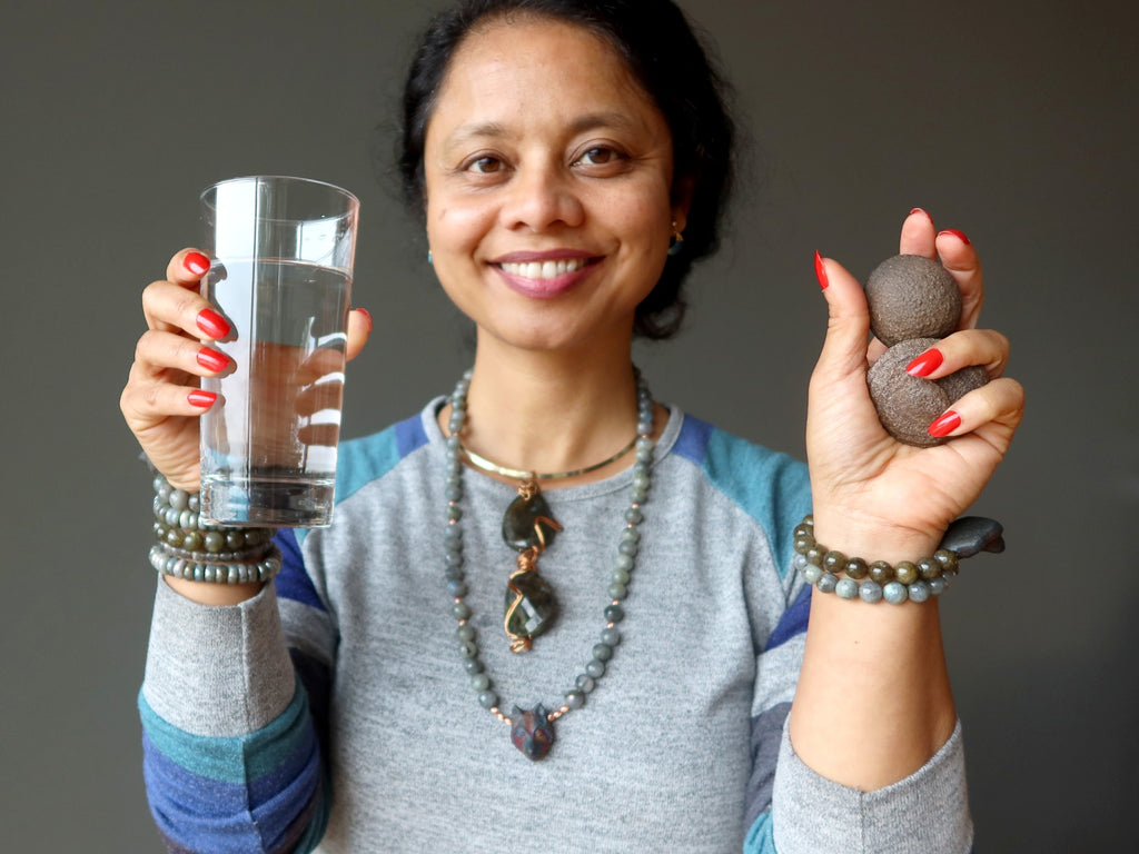 sheila of satin crystals holding a glass of water a pair of moqui marbles, wearing labradorite jewelry