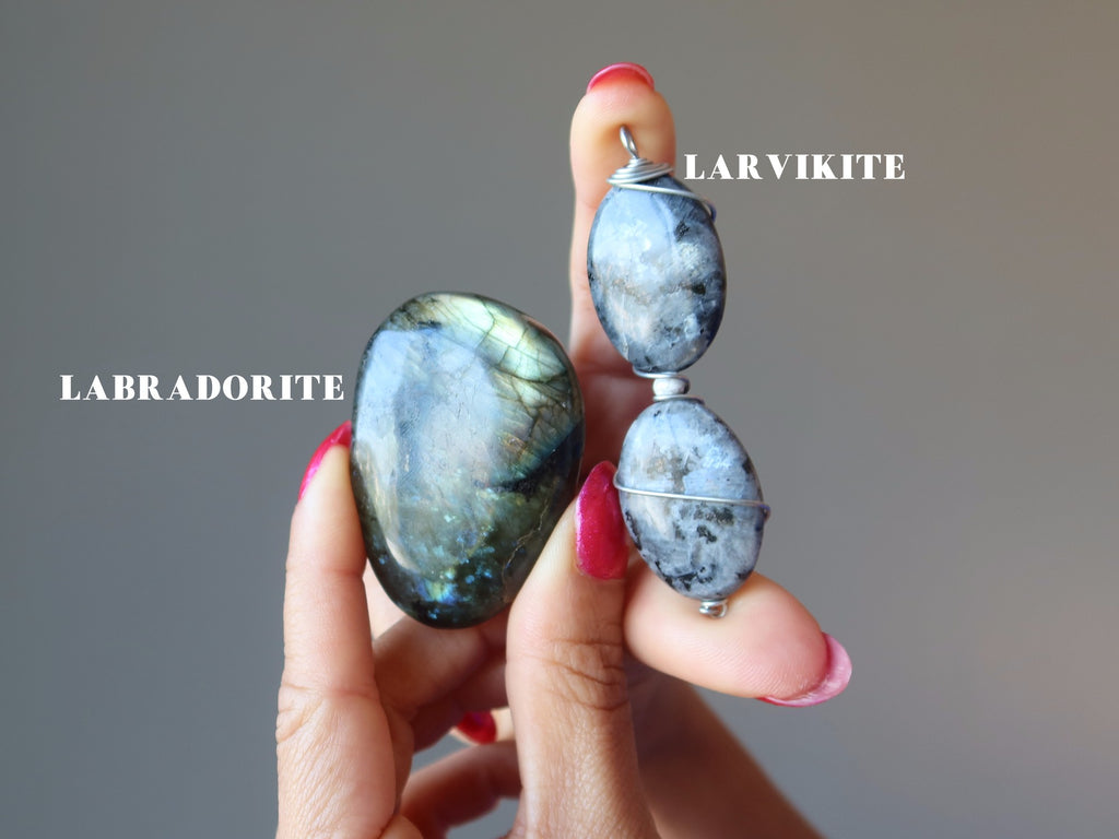 hand holding a labradorite stone and a larvikite pendant