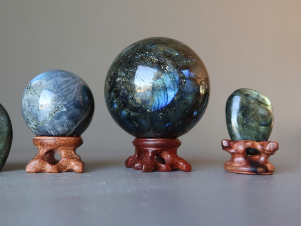 two labradorite spheres and a labradorite polished stone in wood display stands