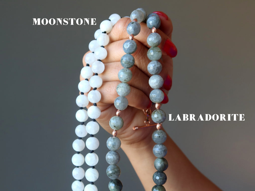 hand holding up white moonstone necklace and a faceted labradorite necklace