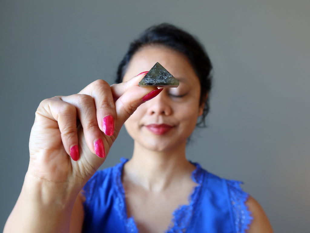 sheila of satin crystals holding a labradorite pyramid at her third eye chakra