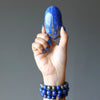 hand wearing three lapis lazuli stretch bracelets holding up a lapis palm stone oval slab