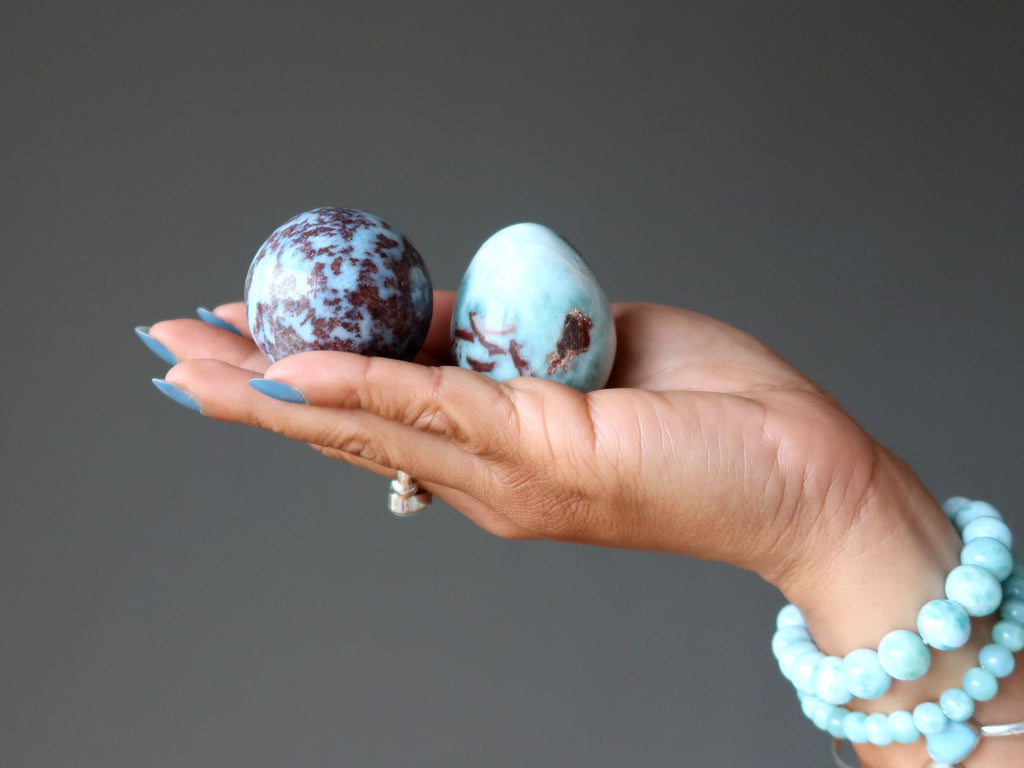 red larimar sphere and egg in palm of hand