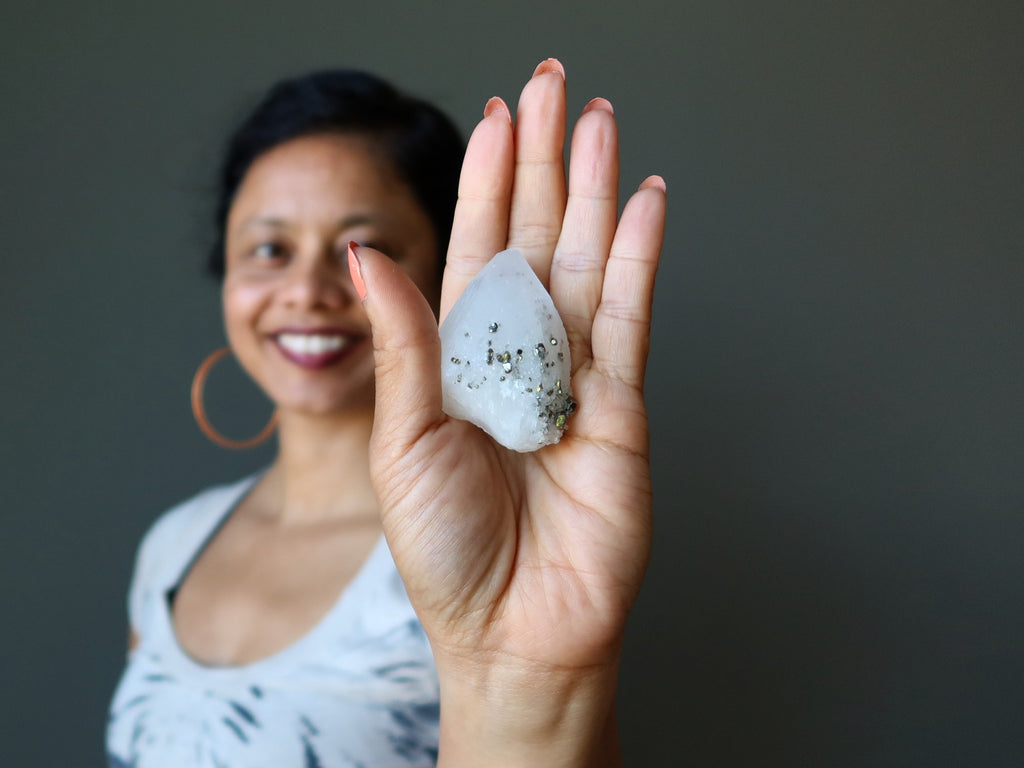 female model holding a quartz pyrite crystal in her palm