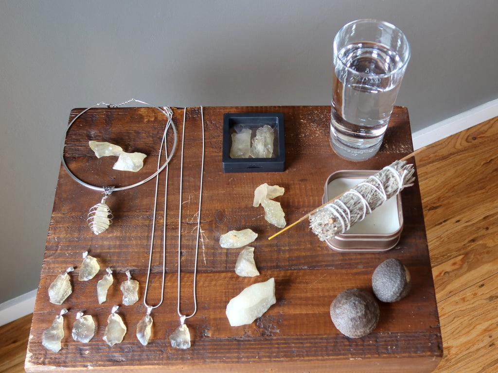 yellow libyan desert glass raw and jewelry, sage, candle, incense, moqui marbles, glass of water