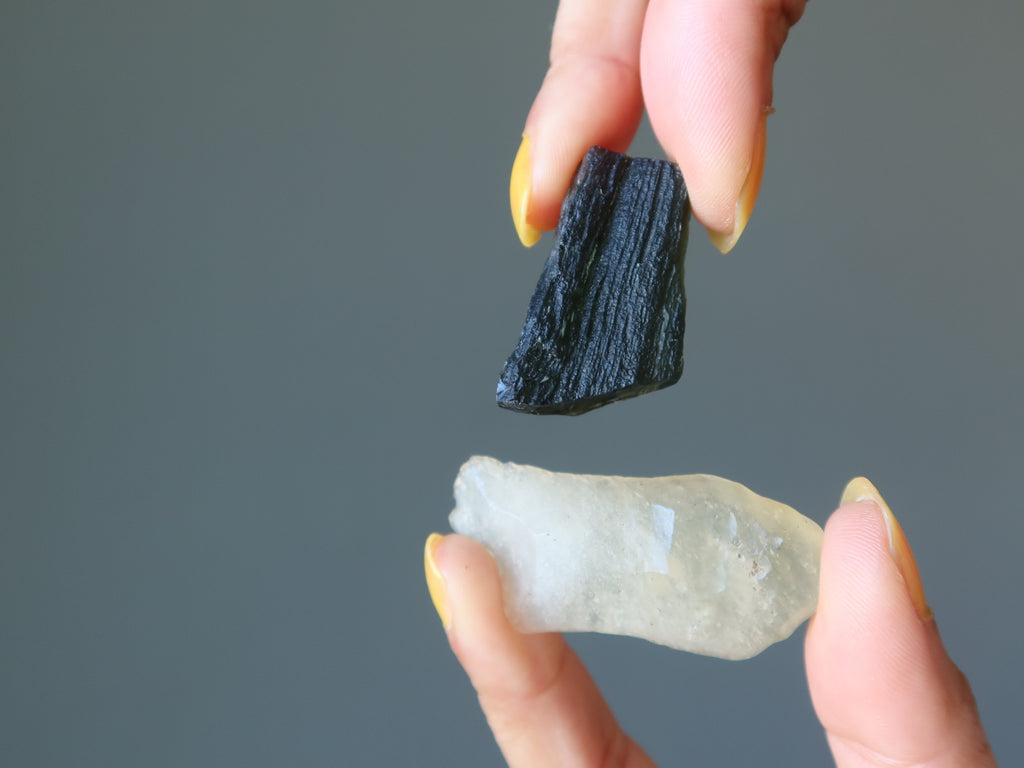 hands holding moldavite and libyan desert glass