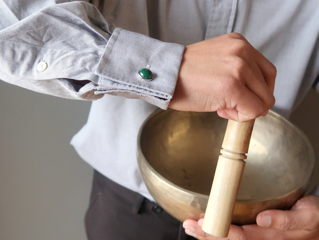 man playing singing bowl with malachite cufflinks on